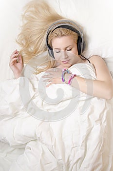 Gorgeous blonde girl lying in bed, listening relaxation music