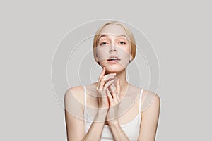 Gorgeous bonde woman touching her face isolated on grey background. Beauty, cosmetics, skincare, glamour photo