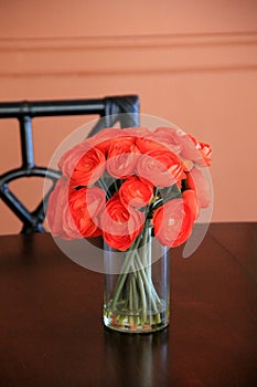 Gorgeous bouquet of bright red-orange flowers in simple vase on table