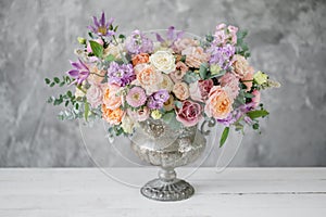 Gorgeous bouquet of different flowers. floral arrangement in vintage metal vase. table setting. lilac and peach color