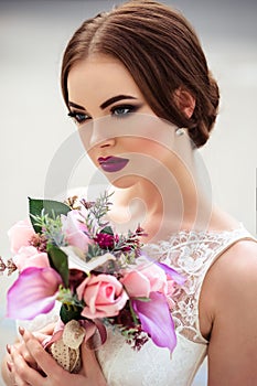 Gorgeous bride with fashion makeup and hairstyle in a luxury wedding dress