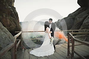 Gorgeous bride, groom kissing and hugging near the cliffs with stunning views