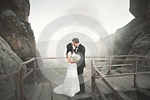 Gorgeous bride, groom kissing and hugging near the cliffs with stunning views