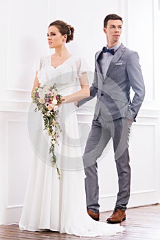 Gorgeous bride with a posy and a handsome groom in retro interior