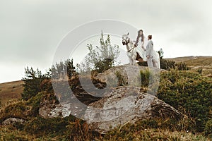 Gorgeous bride riding a white horse and stylish groom, boho wed