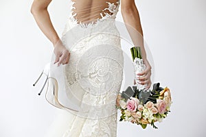 Gorgeous bride with shoes and bouquet on background photo