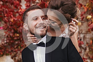 Gorgeous bride and stylish groom gently hugging and smiling at w