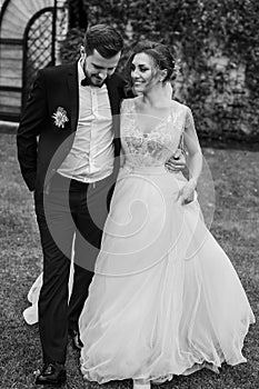 Gorgeous bride and stylish groom holding hands and walking at wa