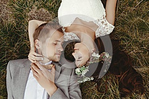 Gorgeous bride and stylish groom lying on top, close up, boho we