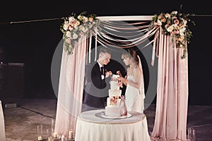 Gorgeous bride and stylish groom tasting their stylish wedding cake