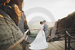 Gorgeous bride and stylish groom walking at sunny landscape, wedding couple, luxury ceremony mountains with amazing view