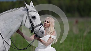 gorgeous bride and white horse are walking at nature in wedding day, romantic portrait