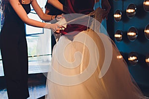 Gorgeous, bride in white luxury dress is getting ready for wedding. Morning preparations. Woman putting on dress.