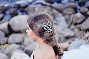 Gorgeous brunette European type sits in profile on the beach, looking romantically into the distance. Beautiful hair