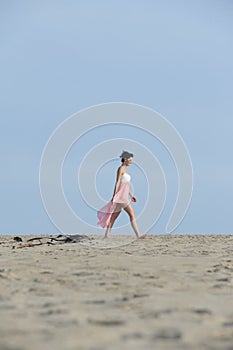 Gorgeous brunette woman in dress walking in the desert sand