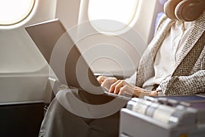 Gorgeous businesswoman on the plane in a business class seat, using laptop computer