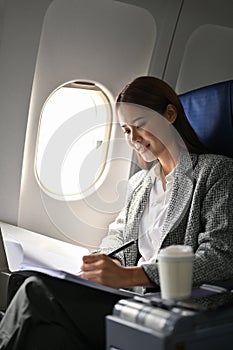 Gorgeous businesswoman reading a meeting proposal report during flight