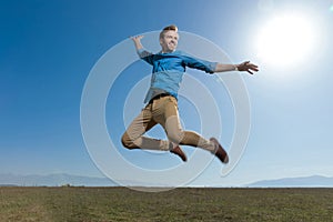 Casual man wearing blue shirt jumping high to the sky