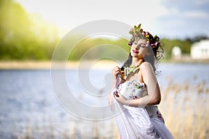 Gorgeous Caucasian Brunette Woman in Decorated Dress and Flowery Chaplet with Butterflies. Posing Against Bright Sunlight