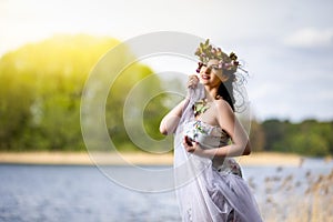 Gorgeous Caucasian Brunette Woman in Decorated Dress and Flowery Chaplet with Butterflies. Posing Against Bright Sunlight