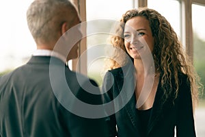 Gorgeous Caucasian businesswoman smiling with confidence, having handshake with businessman as foreground, concept of business