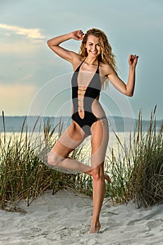 Gorgeous Caucasian girl with slim fit body in black swimsuit enjoying summer time.