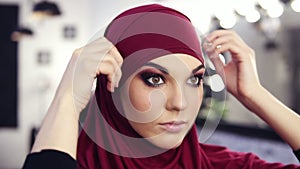 Gorgeous caucasian looking girl at her 20`s puts on purple chiffon hijab or traditional arabic head cover.