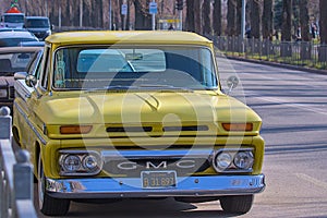 Gorgeous classic yellow 1965 GMC pickup truck parked outdoors on a sunny day.