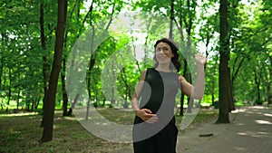 Gorgeous confident pregnant lady strolling outdoors looking away gesturing thumb up smiling. Portrait of happy beautiful