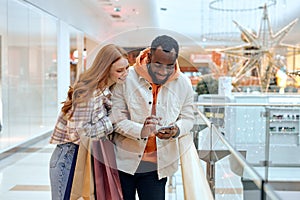 gorgeous diverse cheerful couple using cellphone when shopping