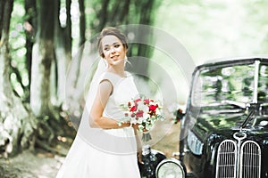 Gorgeous elegant bride posing near stylish retro black car Luxury wedding in vintage style. Portrait