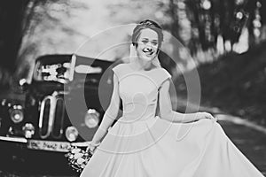 Gorgeous elegant bride posing near stylish retro black car Luxury wedding in vintage style. Portrait