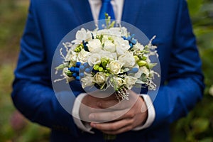 gorgeous elegant groom in blue suit holding stunning stylish bouquet