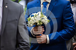 gorgeous elegant groom in blue suit holding stunning stylish bouquet