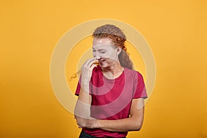 Gorgeous European girl laughing and closing her mouth with a right hand.