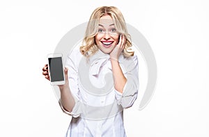 Gorgeous excited woman showing blank screen mobile phone over white background, celebrating victory and success.