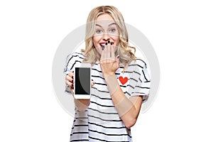 Gorgeous excited woman showing blank screen mobile phone over white background, celebrating victory and success. Excitement.