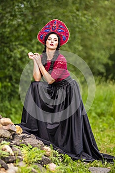 Gorgeous Fashion Brunete Woman In Russian Style Kokoshnik Outdoors Against Batch of Stones