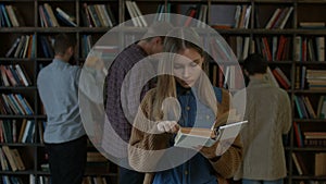 Gorgeous female student reading a book in library