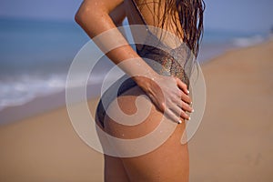 Gorgeous figure of a girl on the beach in a shiny swimsuit