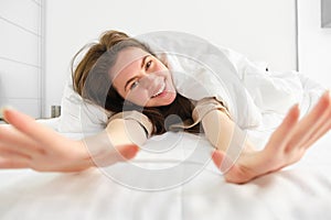 Gorgeous girl laughing and smiling, stretching in hotel bed, enjoying sleepy morning, good nap