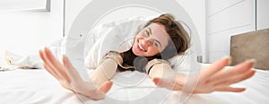 Gorgeous girl laughing and smiling, stretching in hotel bed, enjoying sleepy morning, good nap