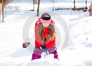 Gorgeous girl wearing a red coat shoveling snow