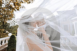 gorgeous happy luxurious brunette bride and elegant stylish groom standing under a veil