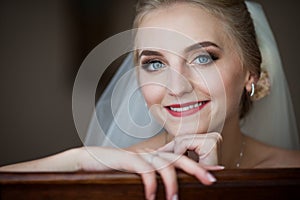 Gorgeous innocent blonde bride posing while sitting on chair, fa