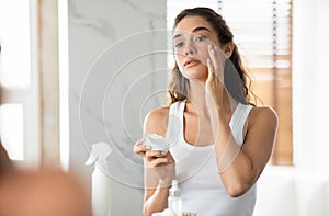 Gorgeous Lady Moisturizing Skin Applying Facial Cream In Modern Bathroom