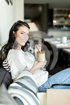 Gorgeous lady sipping coffee in a bar in a leisurly posture