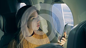 Gorgeous lady is using her phone while flying on the aircraft