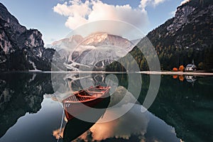 Gorgeous landscape. Wooden boat on the crystal lake with majestic mountain behind. Reflection in the water. Chapel is on