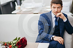 Gorgeous man in tuxedo waiting for a woman, on a date